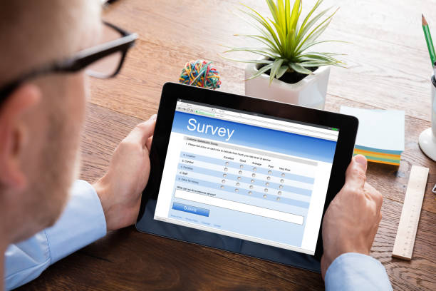 Person Filling Online Survey Form On Digital Tablet At Wooden Desk